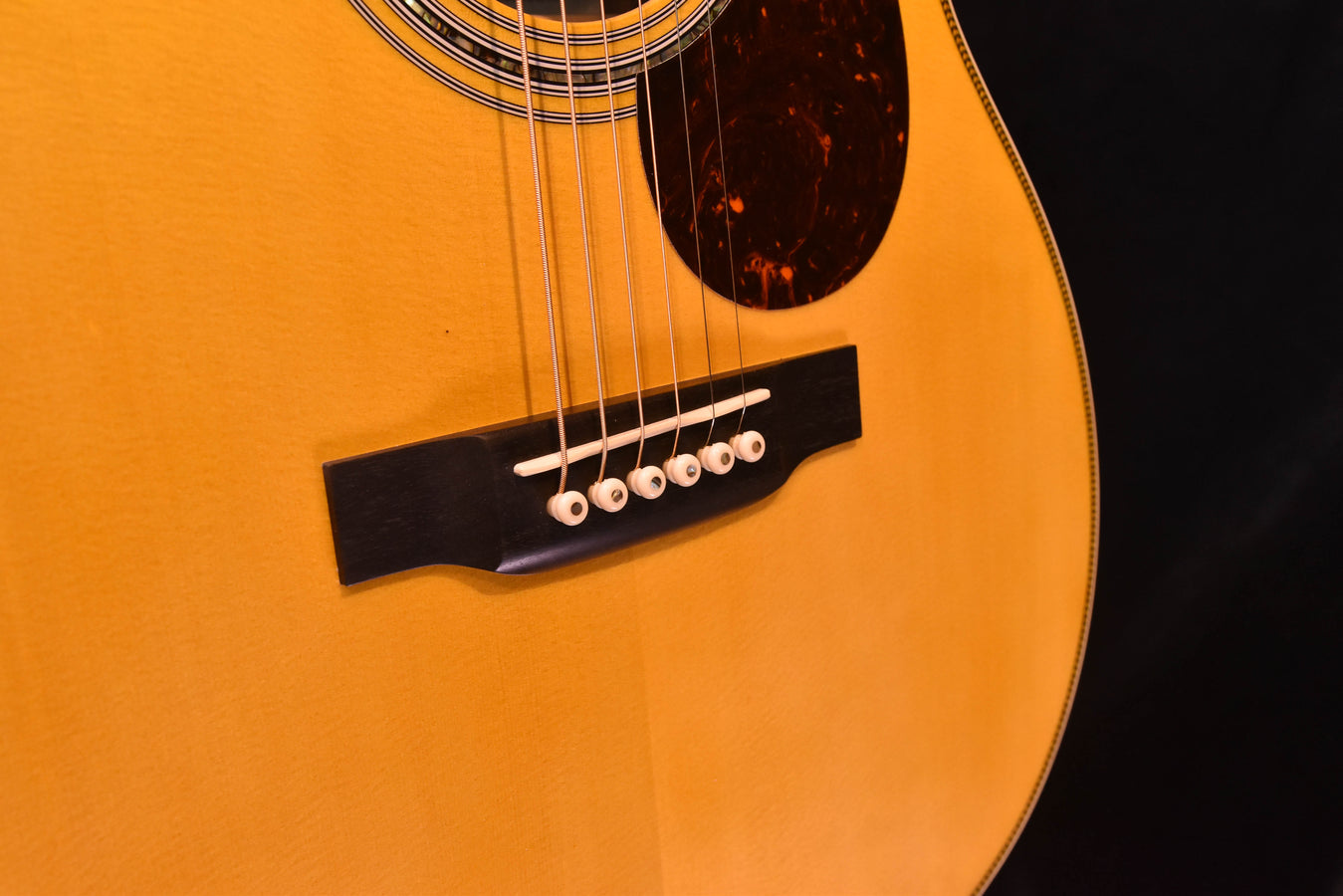 Acoustic-electric guitar bridge with black bridge plate and 6-saddle string setup
