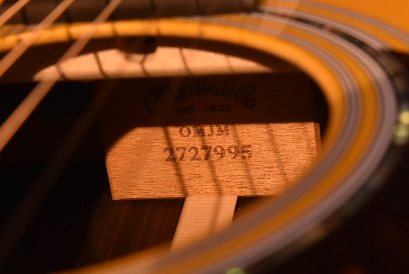 Acoustic-electric guitar bridge plate marking and serial number close-up