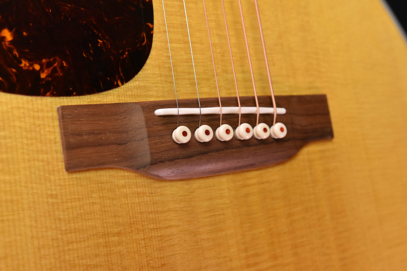 Acoustic guitar bridge with white saddle and six strings