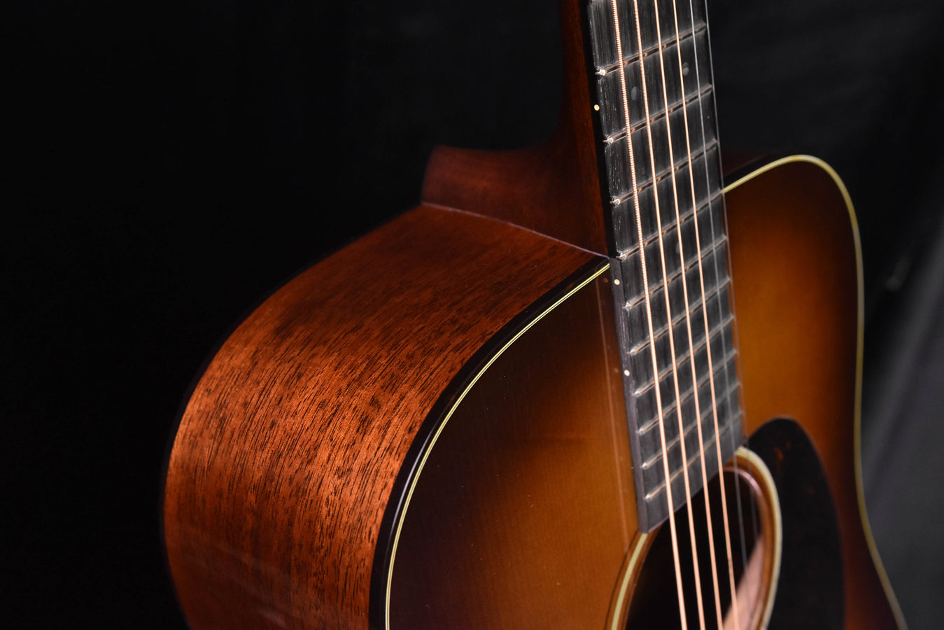 Side view of amber burst acoustic guitar neck and body join