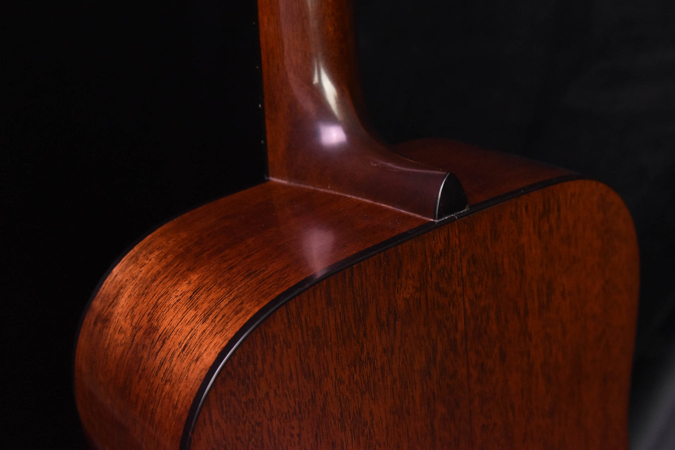 Amber burst acoustic guitar back close-up showing heel and neck joint