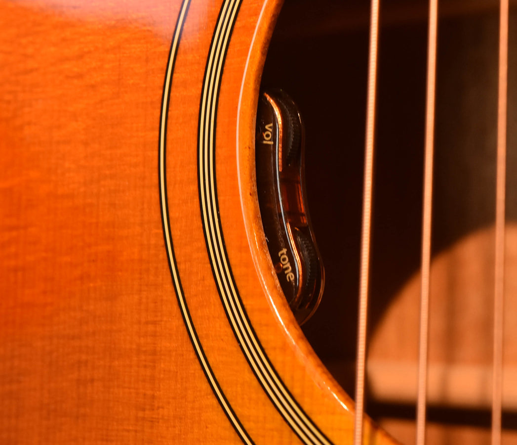 Acoustic guitar side close-up with black and gold binding lines