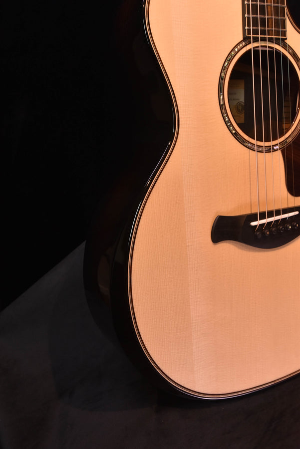 Side view of the acoustic-electric guitar body and soundhole on light wood