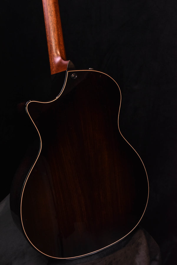Acoustic-electric guitar body close-up with dark finish, neck joint, and gold binding