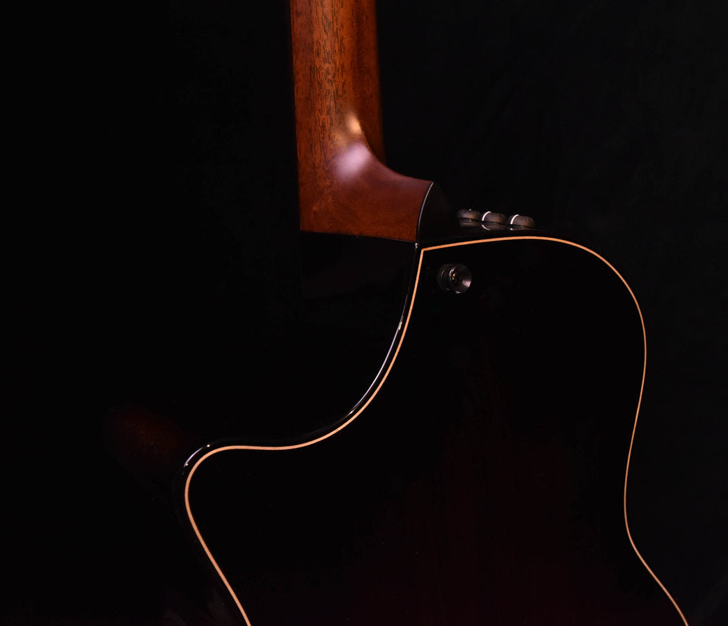 Acoustic-electric guitar neck and upper bout close-up with dark body and gold trim