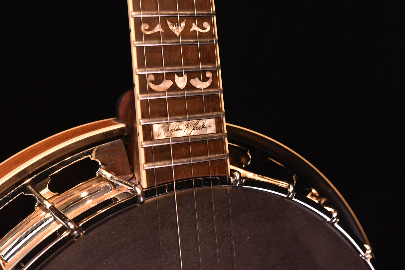 Banjo neck close-up with engraved inlays and multi-dot fret markers