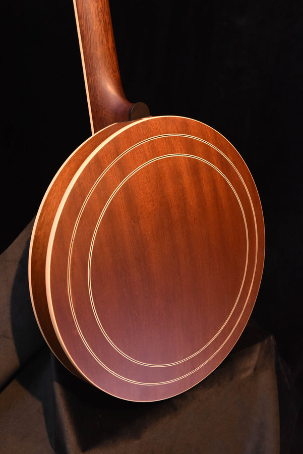 Banjo resonator close-up with multiple cream-colored ring inlays and wood grain