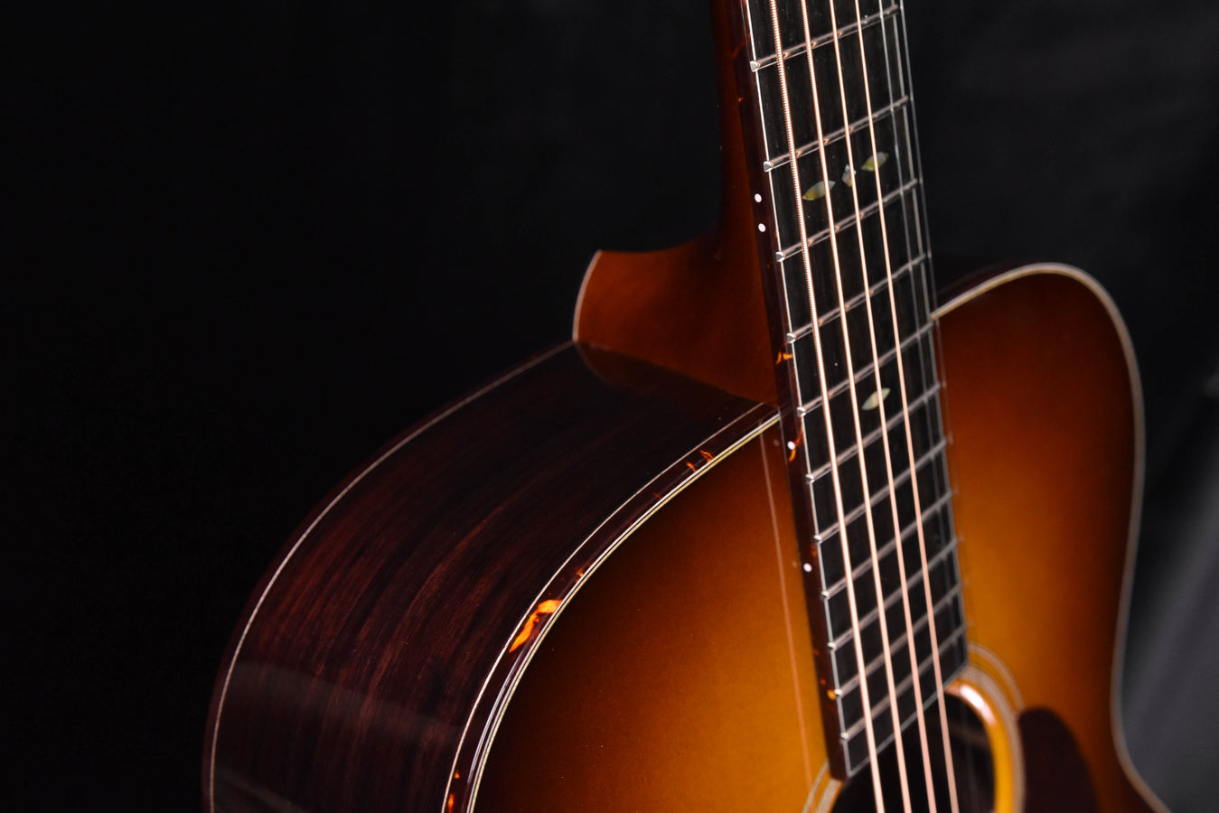 OM acoustic guitar body close-up showing side wood binding and neck joint