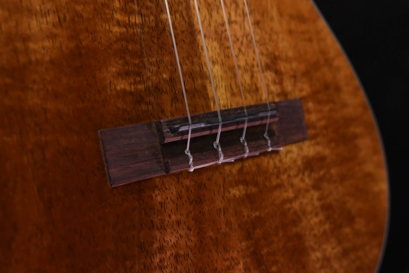Close-up of bridge and strings on koa ukulele soundboard