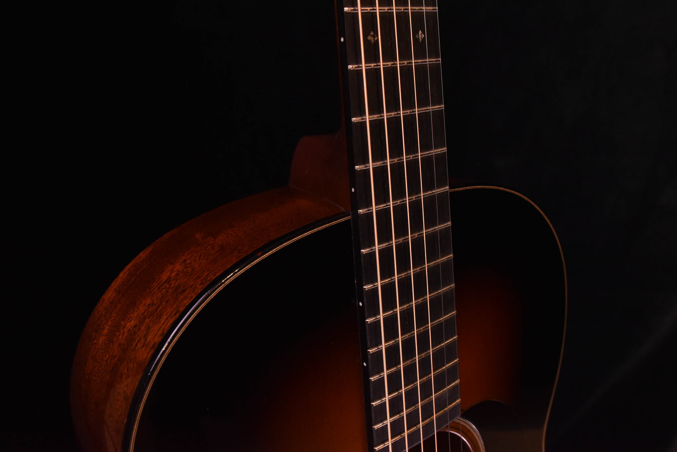 Mahogany-style guitar neck and upper bout, dot inlays visible on fretboard