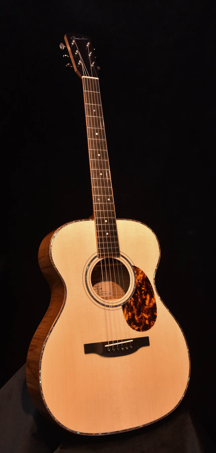 Acoustic guitar with natural top, tortoiseshell pickguard and rosette around sound hole