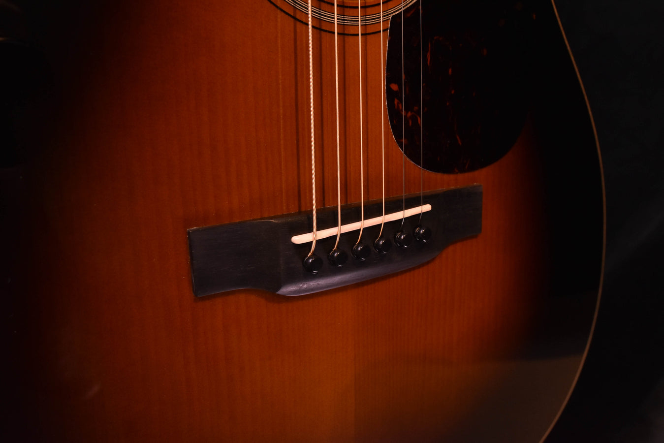 Guitar bridge and strings with black saddle, close-up on lower top