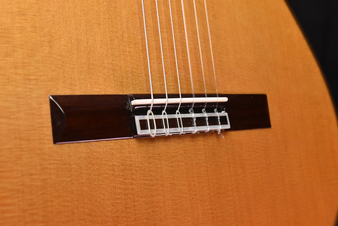 Bridge and strings on classical cedar top guitar, natural wood finish