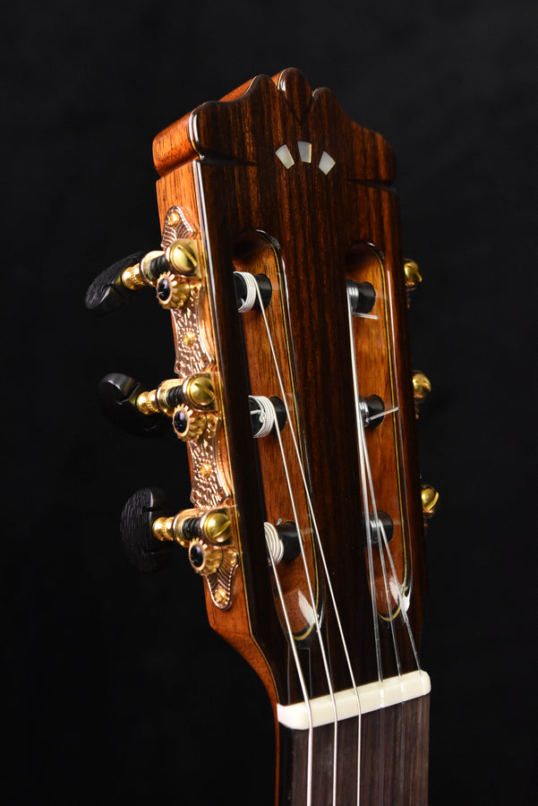 Classical guitar headstock with gold tuning pegs and dark wood finish