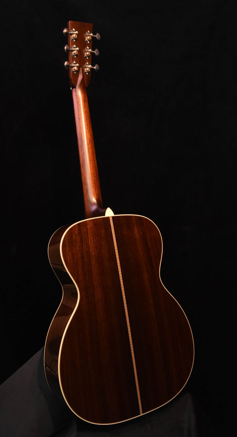 Acoustic guitar back view in dark finish with cream binding and vertical center seam