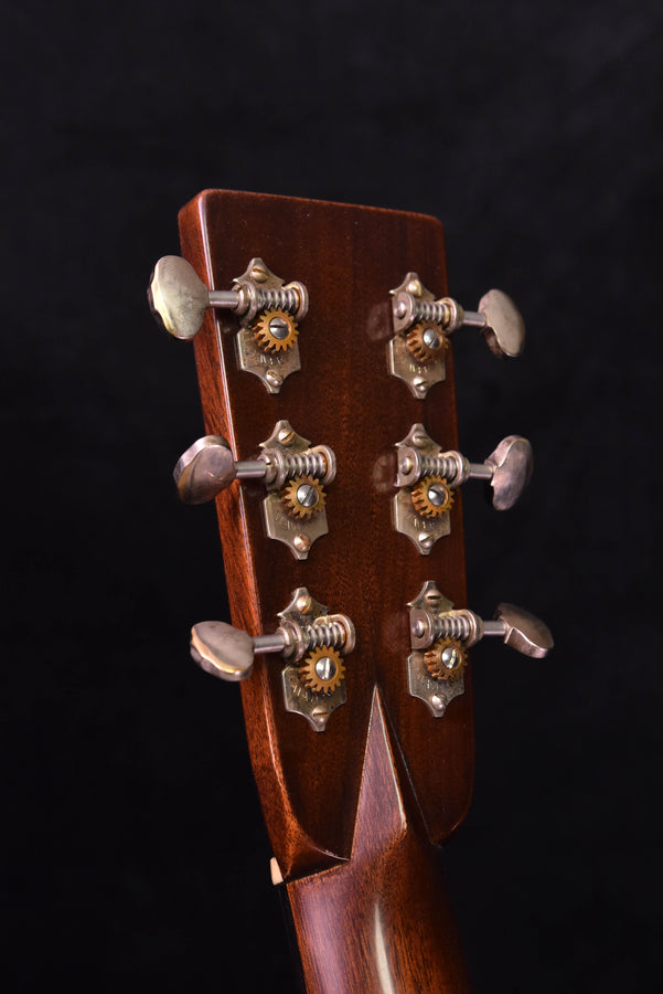 Guitar headstock close-up with tuning machines and metal buttons; Ambertone finish