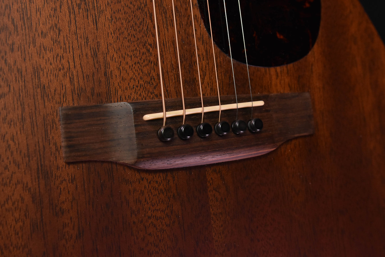Used acoustic guitar close-up of bridge, saddle, and black tuning pegs on body