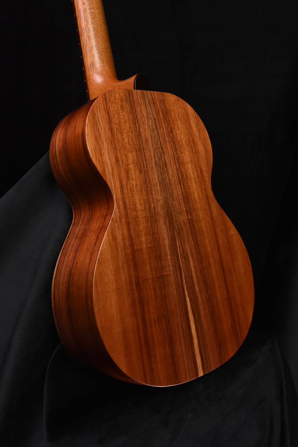 Tenor ukulele back view, natural brown curved wood body with bridge area
