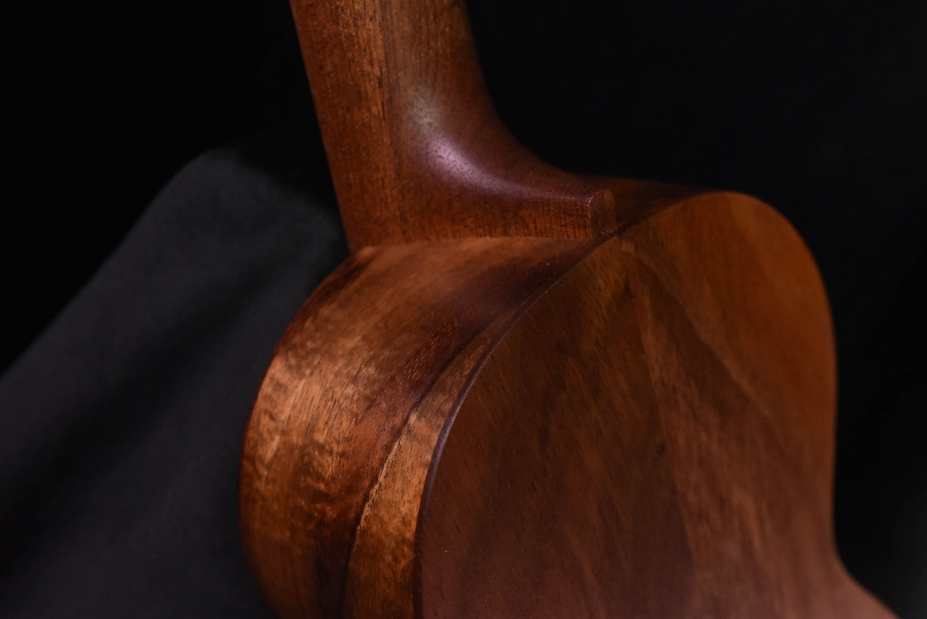 All-Koa concert ukulele, neck joint and body curve with visible wood grain