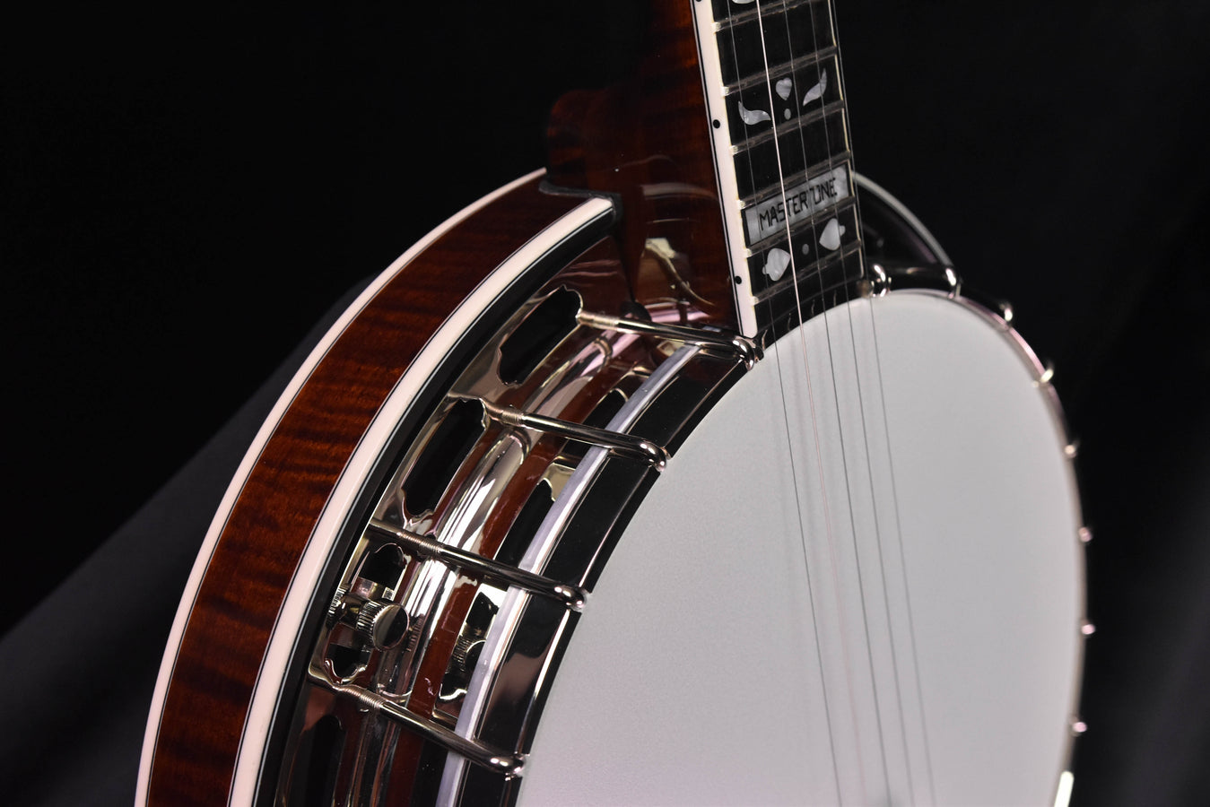 Close-up of banjo neck and rim hardware beside the white drumhead