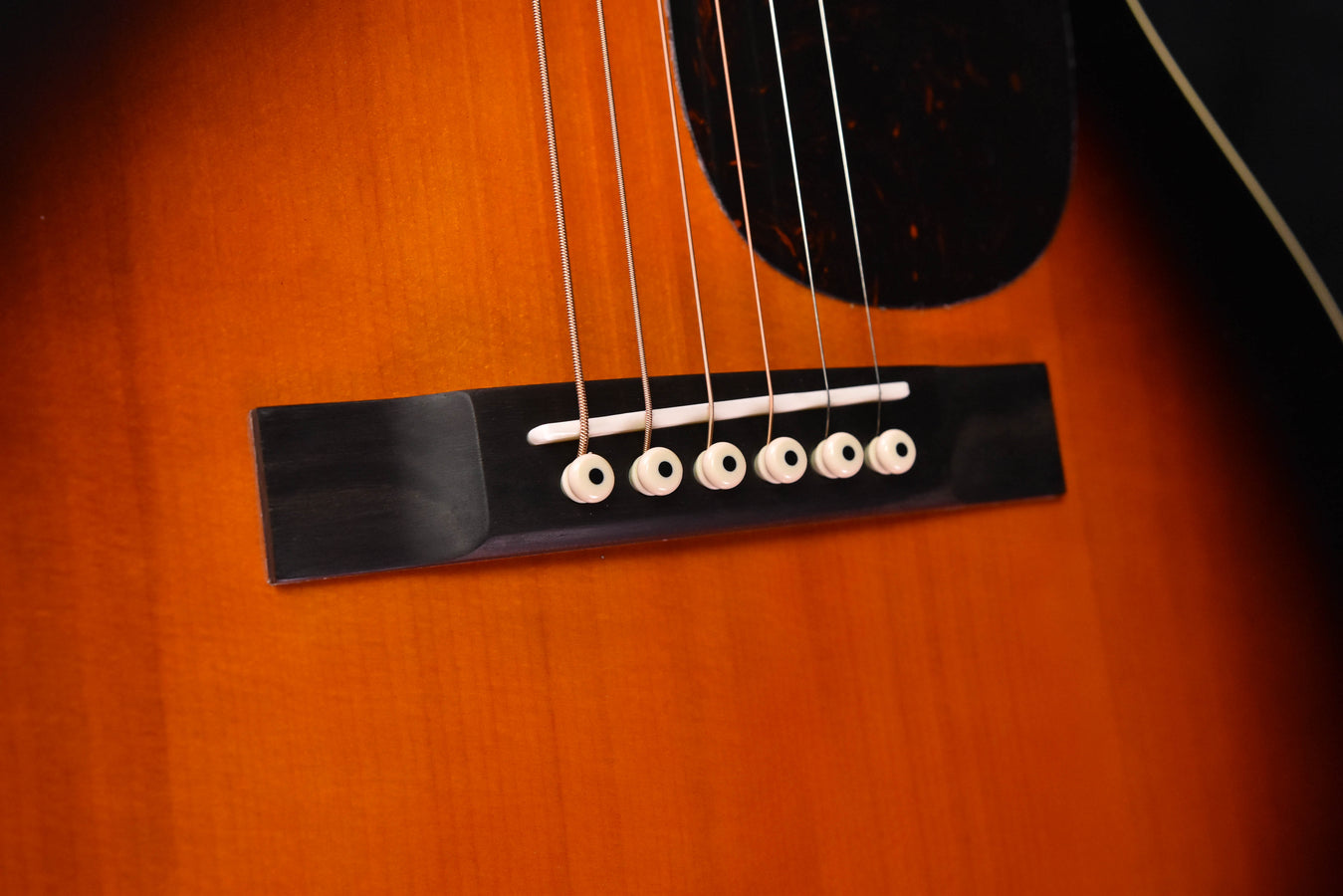 Acoustic guitar bridge area with black bridge plate and 6 bridge pins