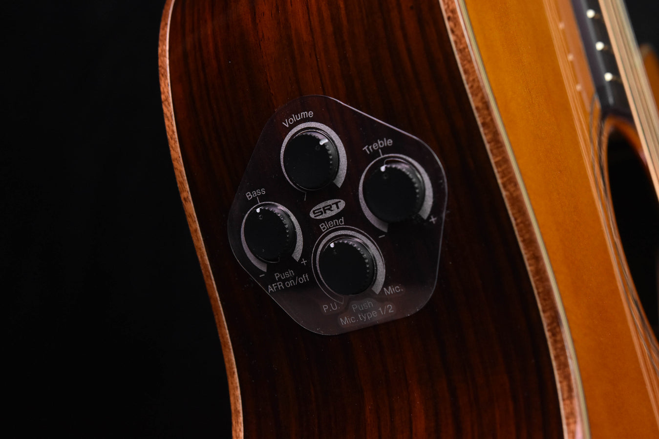 Acoustic-electric pickup control panel with labeled knobs near soundboard