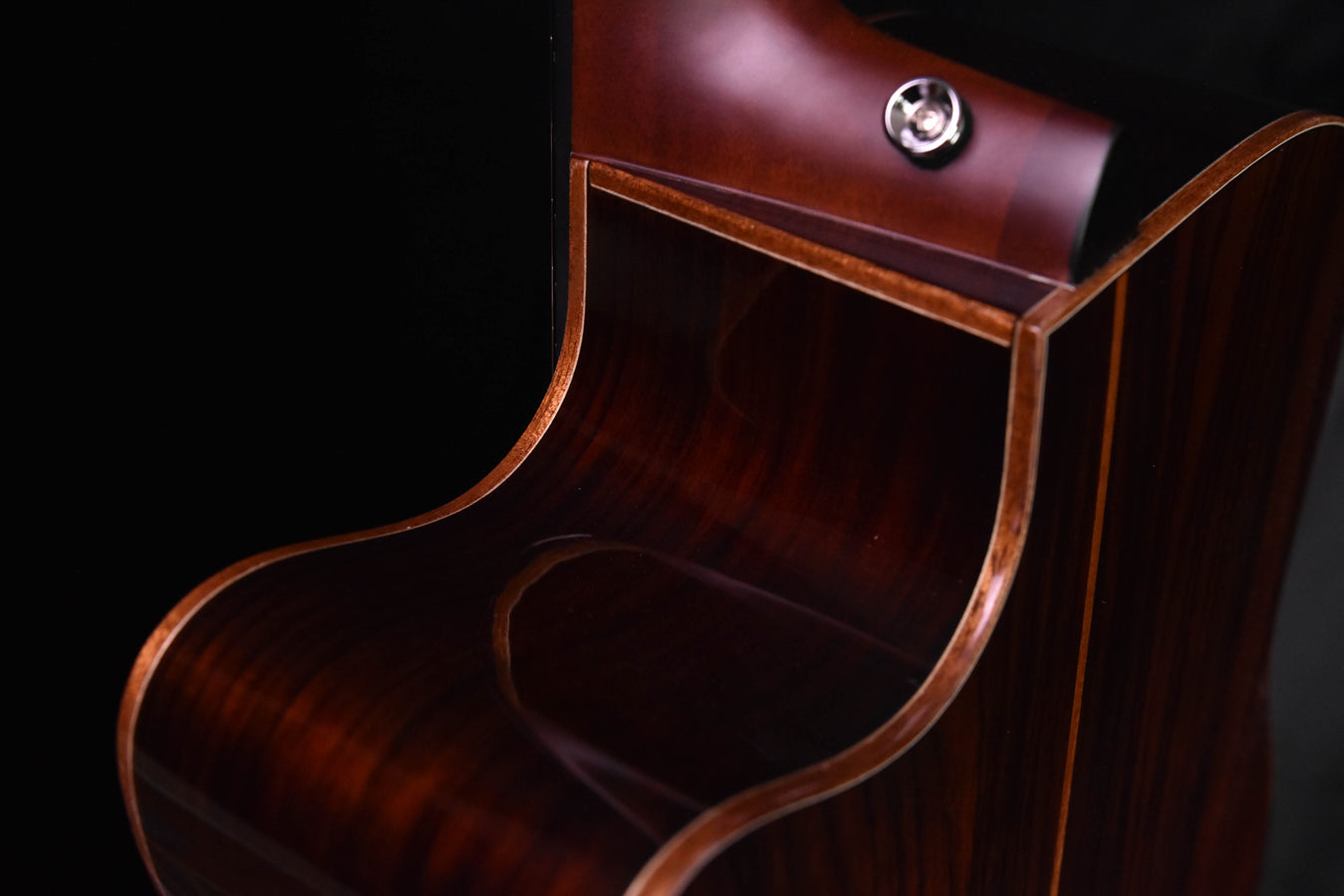 Acoustic-electric guitar lower bout with glossy dark wood grain