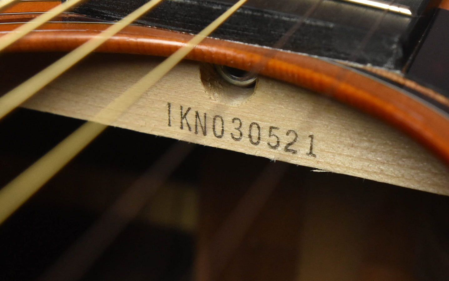 Fretboard wood with stamped serial number IKN030521 visible