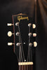 Gibson acoustic guitar headstock, tuning pegs and logo on dark wood