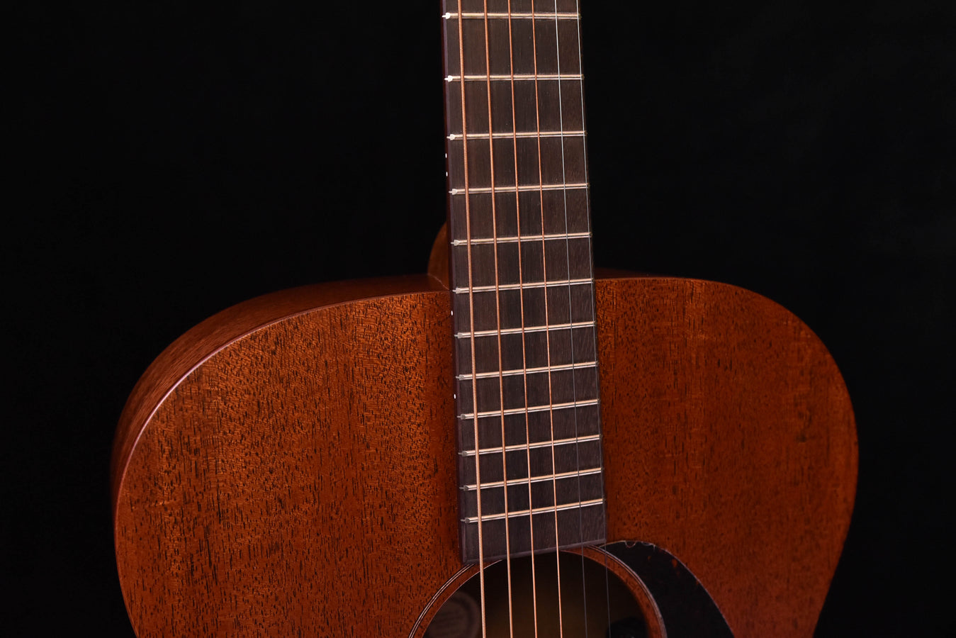 Neck and strings of satin all-mahogany acoustic guitar above the soundhole