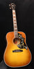 Acoustic guitar with sunburst body, black pickguard with gold hummingbird inlay