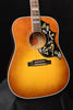 Acoustic guitar front view: sunburst finish, soundhole rosette, hummingbird pickguard