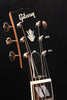 Headstock of an acoustic guitar with Gibson logo and tuning pegs