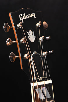headstock of an acoustic guitar with gibson logo and tuning pegs