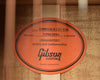 Acoustic guitar warranty label reading “Style HUMMINGBIRD KOA” and “Gibson Custom”