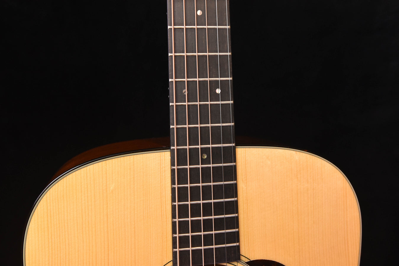 Acoustic guitar neck and upper body, showing frets and light wood soundboard