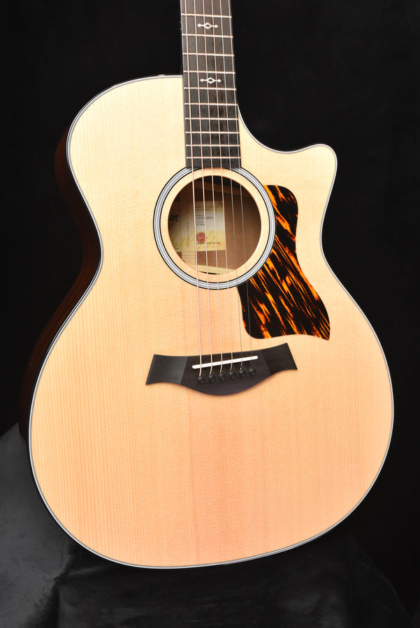 Acoustic-electric guitar front view with natural top, tort-style pickguard, and bridge pins