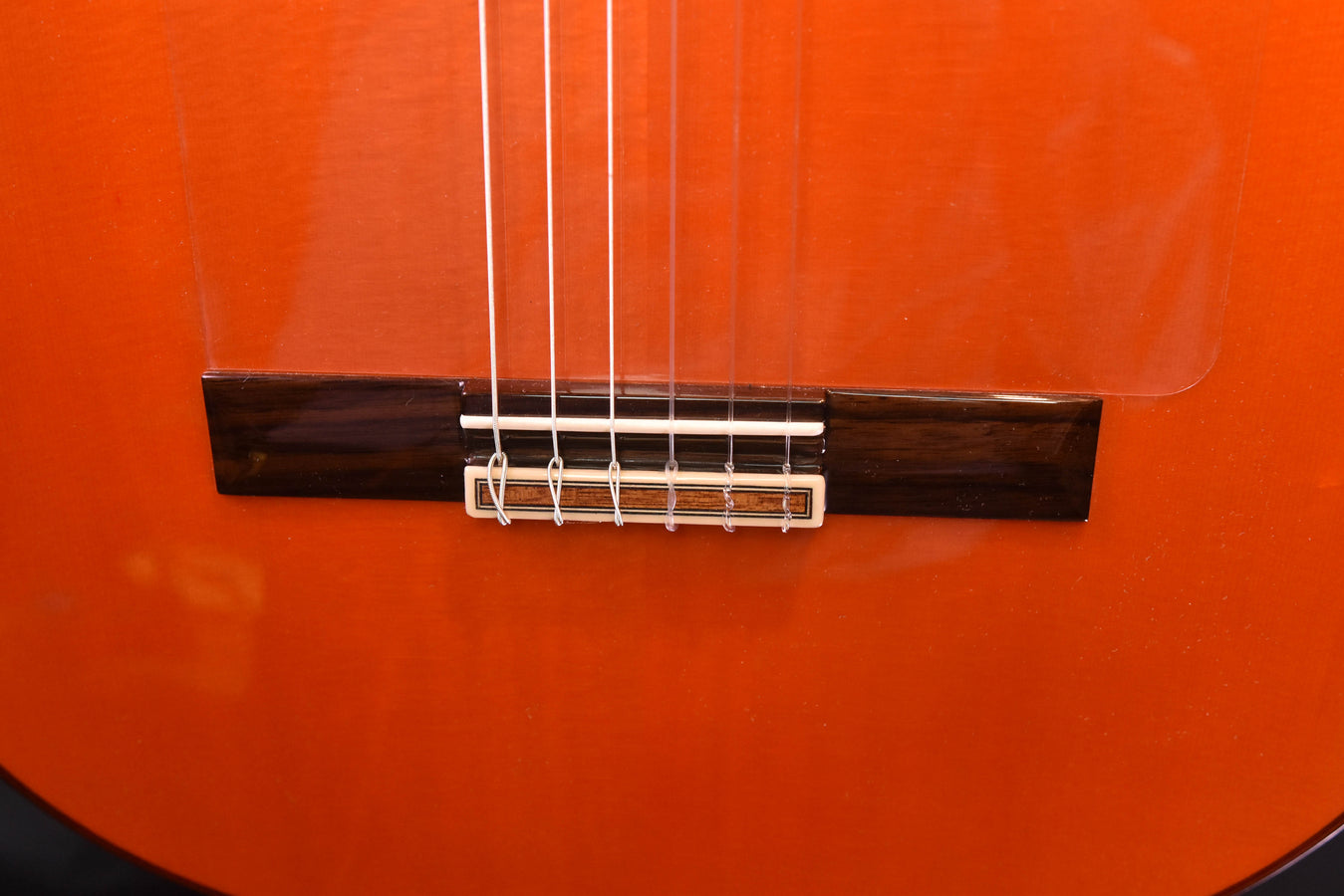 Flamenco guitar bridge with white strings across dark bridge plate