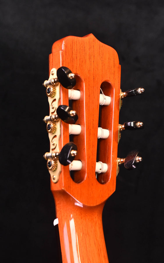 Flamenco guitar headstock front with tuning pegs and glossy warm wood