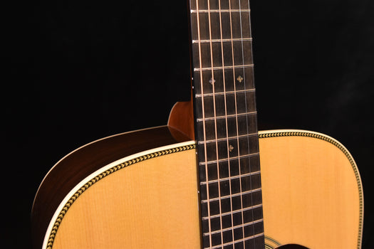 halsansicht einer akustik-gitarre: griffbrett mit bünden und saiten über der decke