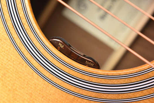acoustic guitar rosette detail with “vol” and “tone” markings inside the sound hole