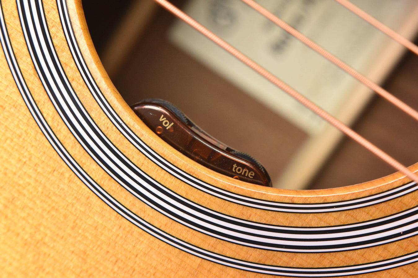 Acoustic guitar rosette detail with “Vol” and “tone” markings inside the sound hole