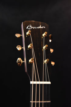 jumbo acoustic guitar headstock with gold tuning machines and branded logo