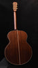 Jumbo acoustic guitar back view in dark wood with gold trim on body edges