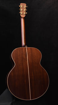 jumbo acoustic guitar back view in dark wood with gold trim on body edges