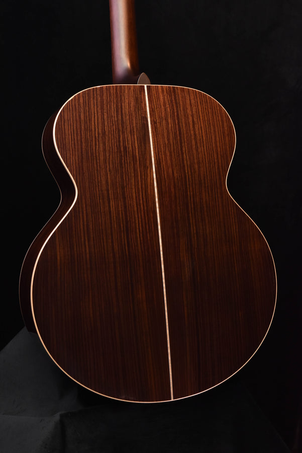 Jumbo acoustic guitar back close-up showing dark wood grain and center seam