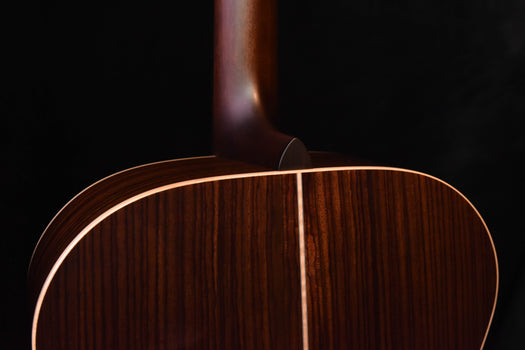 jumbo acoustic guitar upper bout close-up with gold binding and glossy wood finish