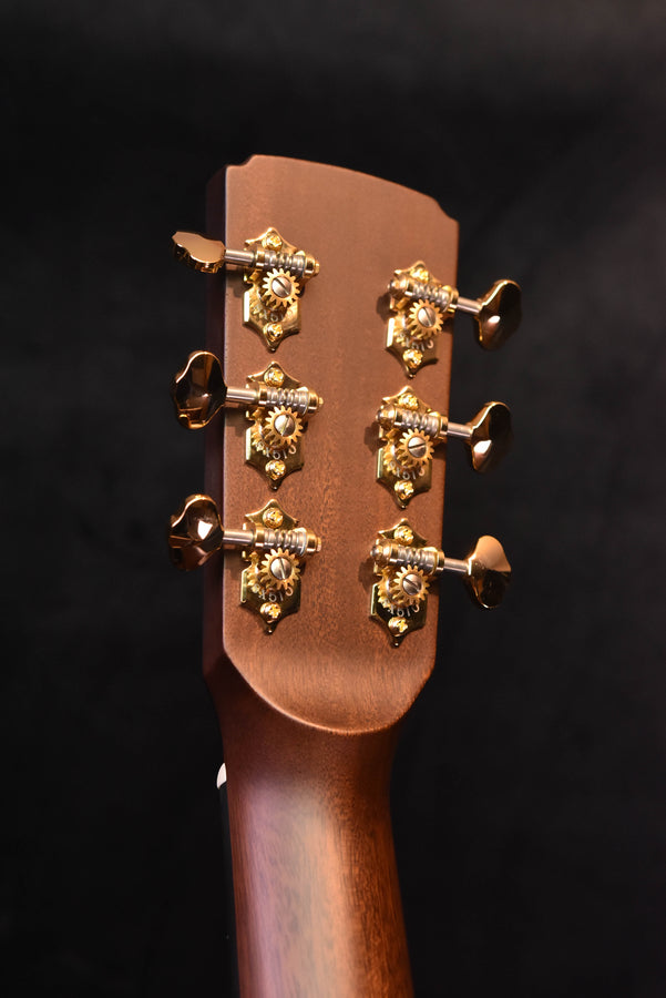 Jumbo acoustic guitar headstock close-up with gold tuners and tuning keys