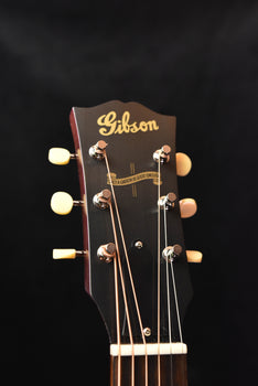 gibson acoustic guitar headstock with tuning pegs and logo
