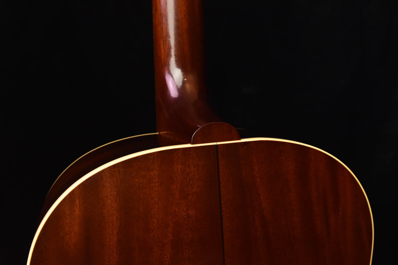Acoustic guitar upper bout with glossy wood finish and gold binding